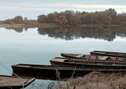 Wooden rowboats moored on a still river with autumn trees reflected in the water
