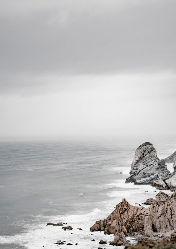 Moody grey seascape with rugged tan cliffs and misty horizon