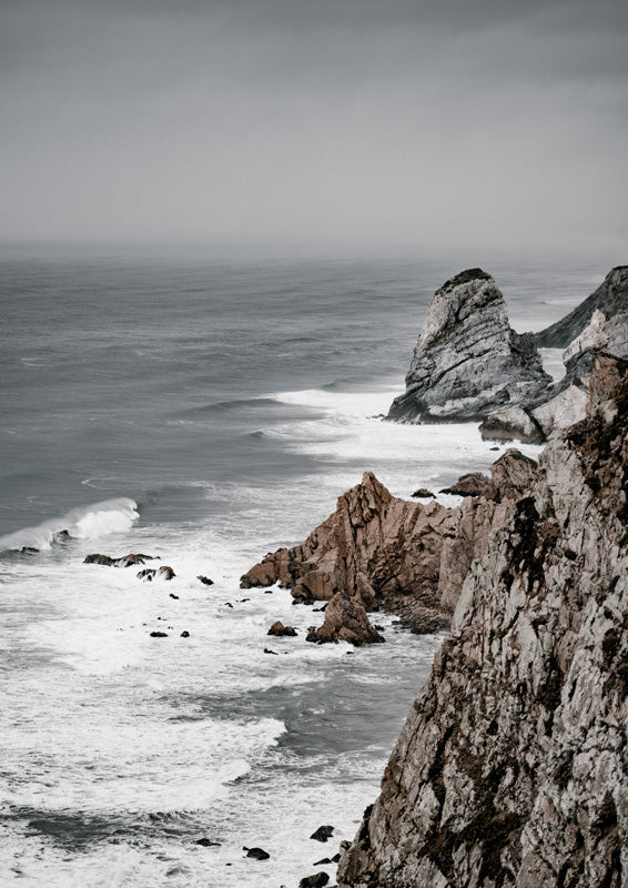 Rugged coastal cliffs with crashing waves under a moody grey sky