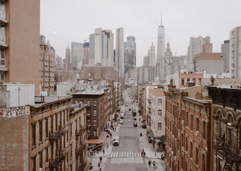Elevated view down a Manhattan street with brick buildings and the downtown skyline beyond