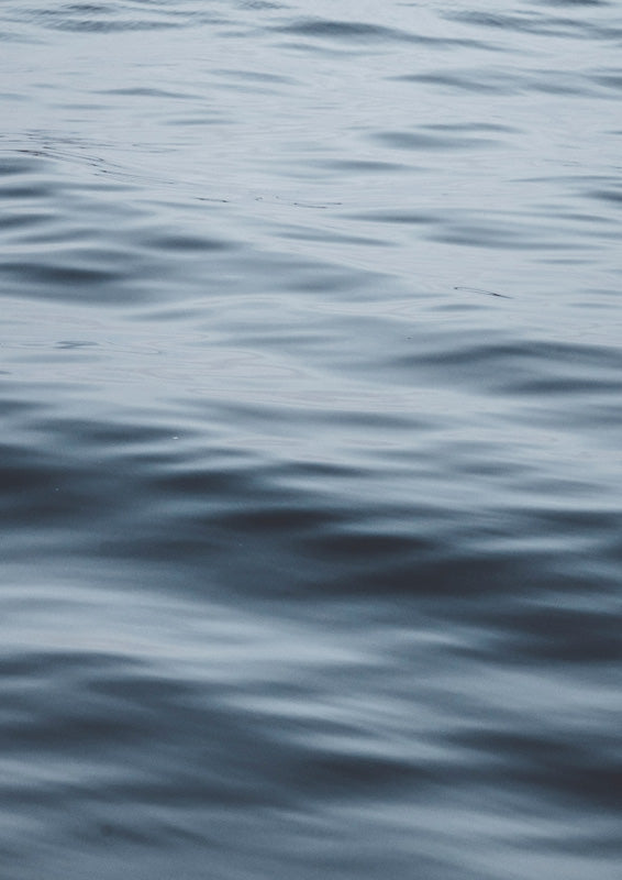 Close-up photograph of rippling blue-grey ocean water with soft light on the surface