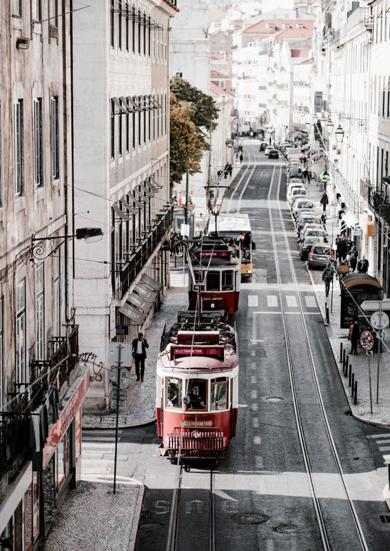 Red and white tram on tracks down a narrow European street lined with stone buildings