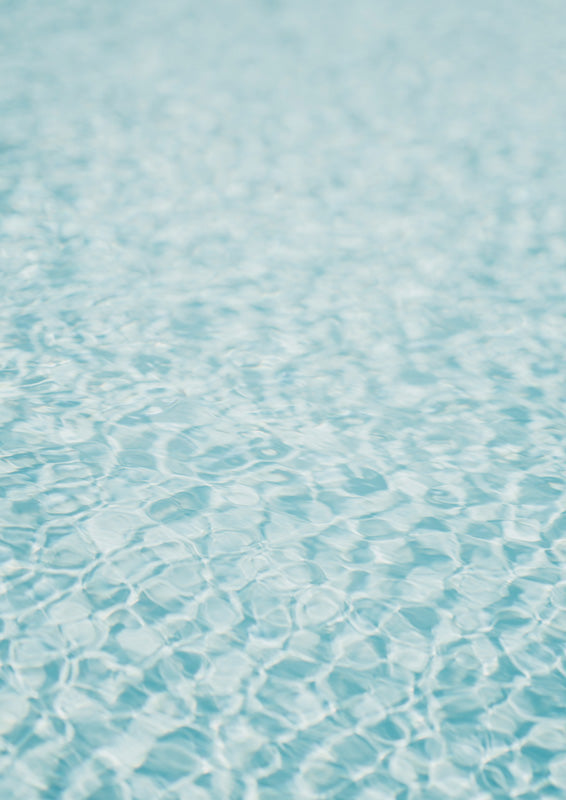 Close-up photograph of rippling turquoise pool water with light patterns