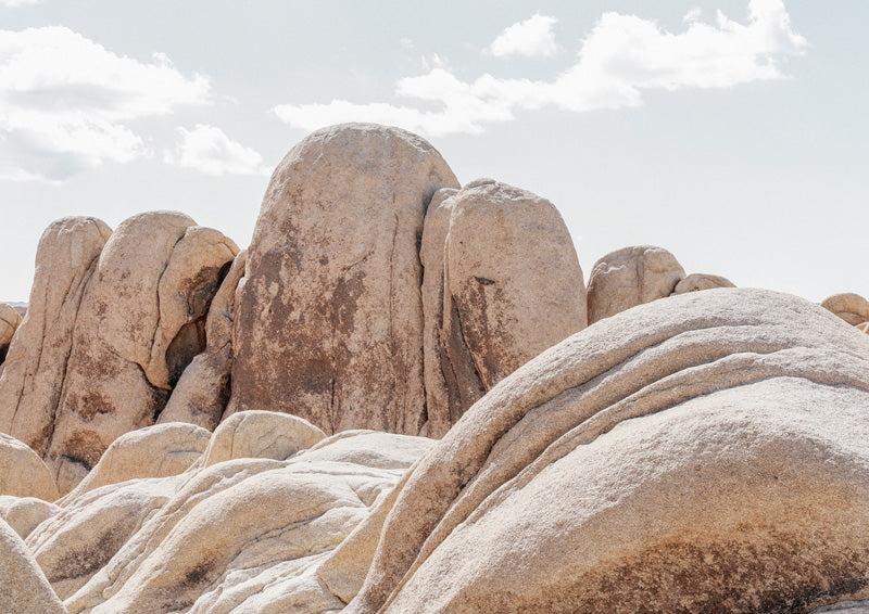 Rounded desert boulders with weathered tan and cream surfaces under a pale cloudy sky