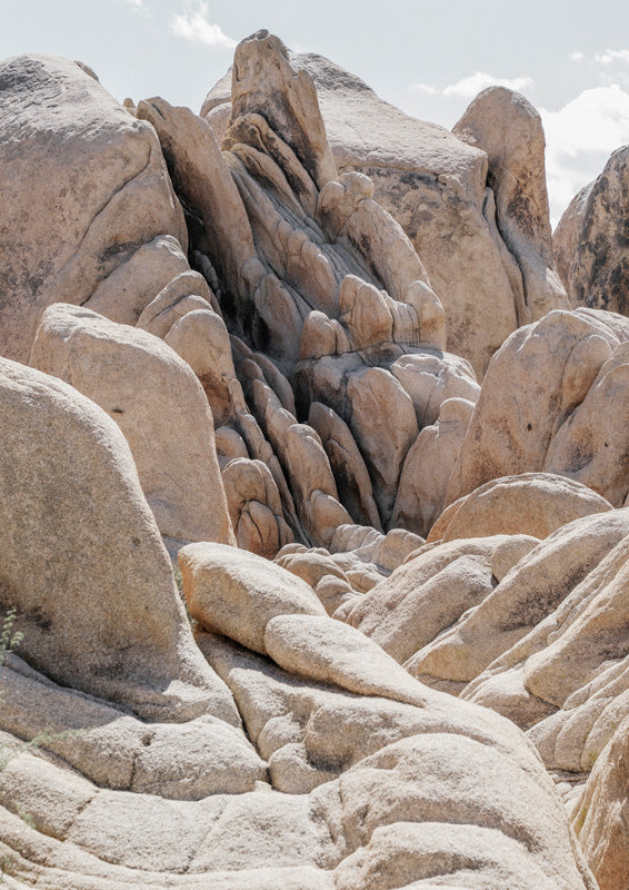 Close-up of weathered sandstone boulders forming a narrow desert rock formation under a pale sky.