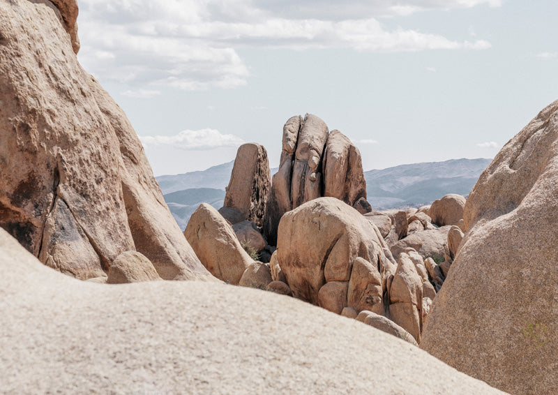 Weathered sandstone boulders in a desert landscape with hazy mountain ridges under a pale blue sky