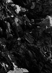 Black and white close-up of jagged, layered slate rock formation with sharp light and shadow