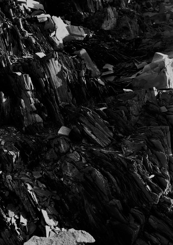 Black and white close-up of jagged, layered slate rock formation with sharp light and shadow