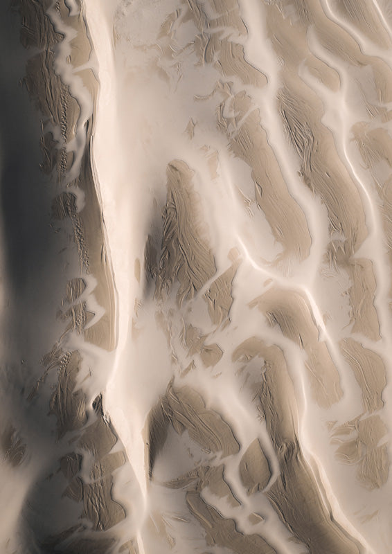 Aerial photograph of sand dunes with rippled texture in beige and cream tones