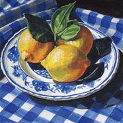 Painting of lemons and leaves on a blue and white plate over a blue gingham tablecloth