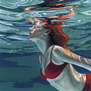 Underwater view of a swimmer in a red swimsuit with red hair, surface reflections above.