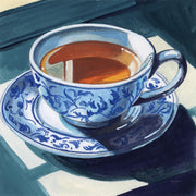 Blue and white porcelain teacup and saucer filled with amber tea on a dark surface