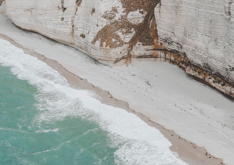Aerial photo of a white cliff face, sandy beach and turquoise sea with breaking waves