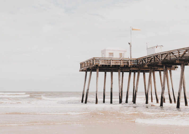 Weathered wooden pier extending over the ocean with soft, hazy coastal tones
