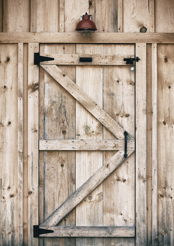 Weathered wooden barn door with iron hinges and a red lamp mounted above