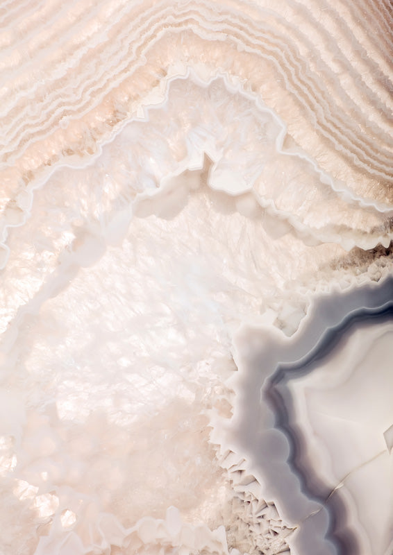 Close-up photograph of banded agate crystal in blush, cream and charcoal tones