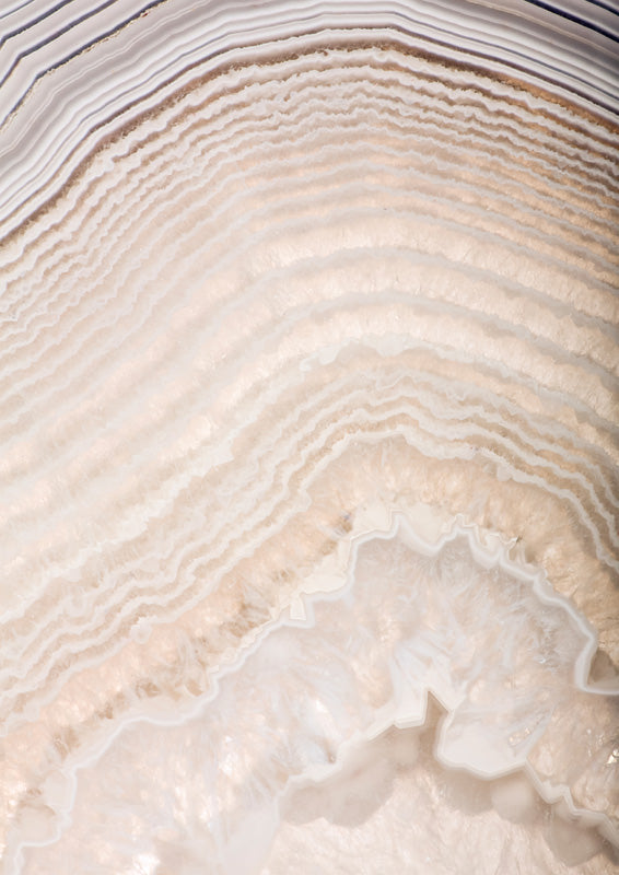 Close-up of banded agate stone in cream and gold tones with curving mineral rings