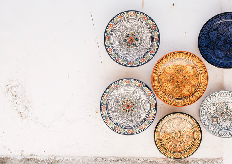 Overhead photo of ornate patterned ceramic plates on a white textured wall