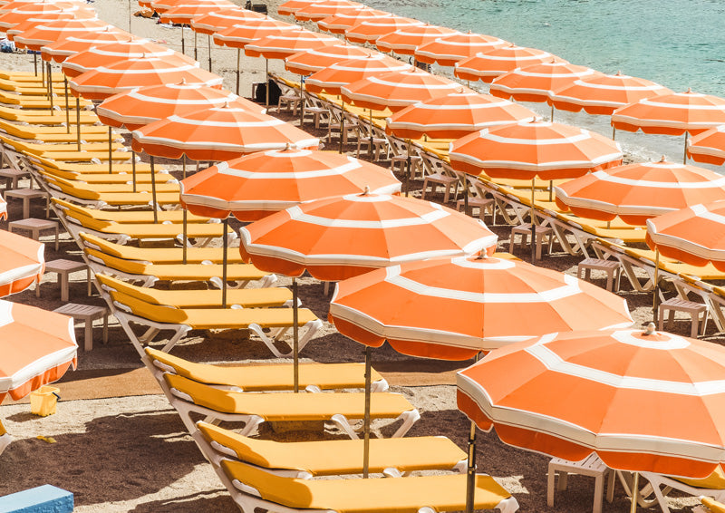Aerial view of orange striped beach umbrellas and yellow loungers in rows on sand