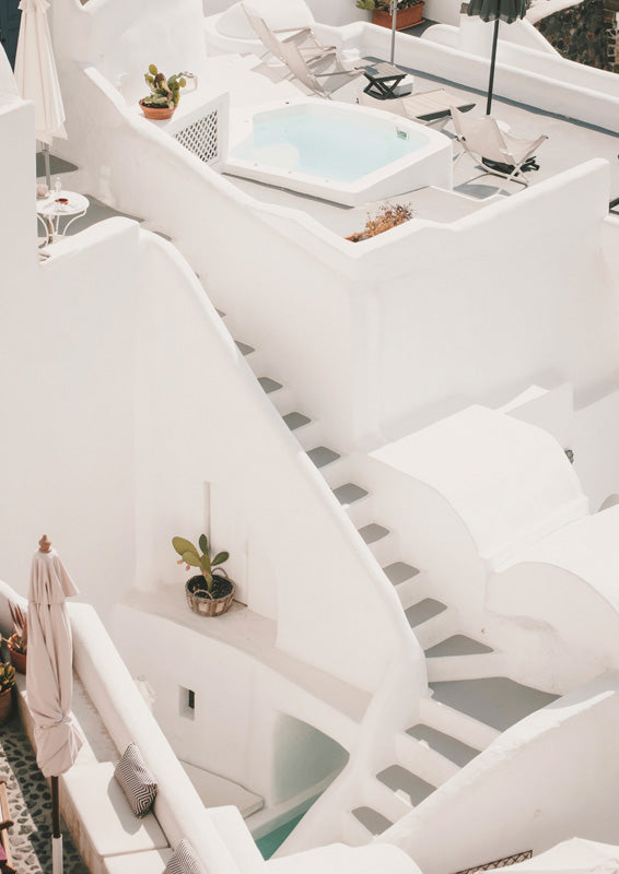 Whitewashed Santorini rooftop with curved stairs, plunge pool, sun loungers and potted cacti