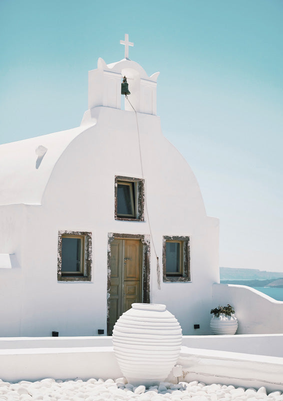 White domed chapel with cross and bell tower, timber door, ribbed urn and sea beyond