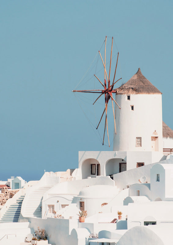 White Santorini windmill and terraced buildings under a clear blue sky