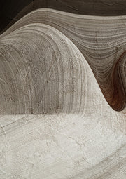Abstract print with curved sand, taupe and brown bands resembling carved rock texture