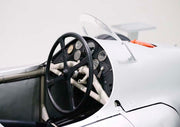 Close-up of a vintage race car cockpit with black steering wheel and round gauges