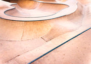 Close-up of curved concrete skate park bowl with warm tan tones and dark seam lines