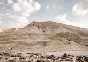Desert landscape with sandy mesas, scrub and a cloudy blue sky