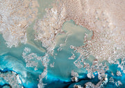 Aerial photograph of coastal shoreline with turquoise water and white lace-like sand patterns