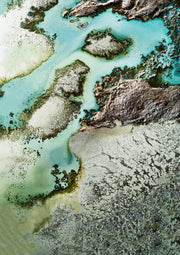 Aerial photograph of turquoise water, sand and rock formations along a coastline
