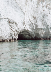 White limestone cliff with a sea cave above clear turquoise water at Milos