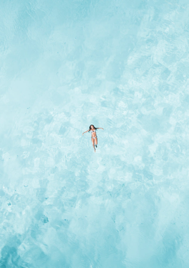 Aerial photo of a swimmer floating on light blue rippling water