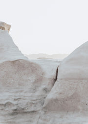Pale limestone rock formations framing a hazy sea and distant mountains